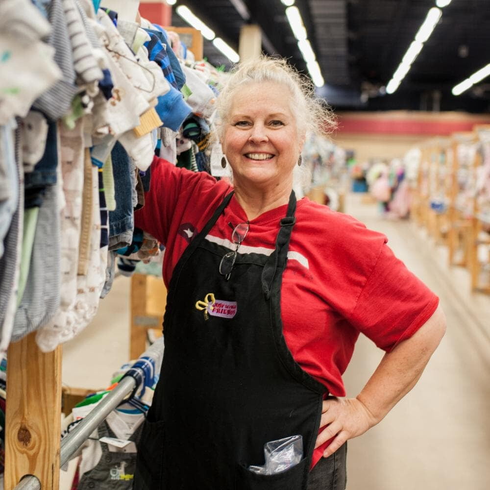 Beautiful mom holds two boys tops—one in each hand—as she shops the deals at her local sale.