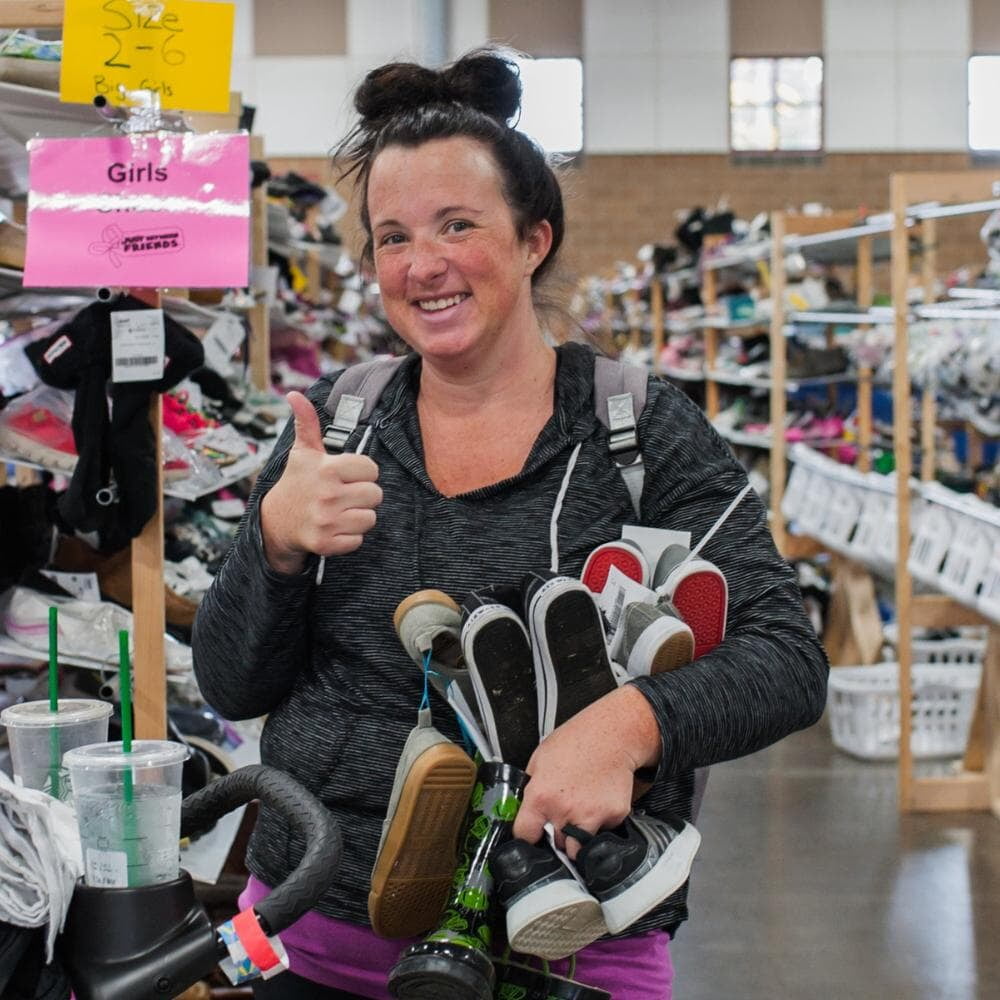 Two masked moms—one holding a child with a mask, the other pregnant—shop for their families at the local JBF sale.